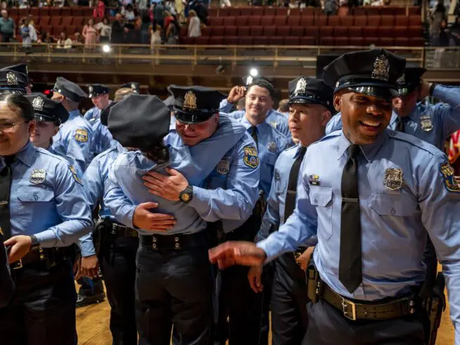 New officers, members of the police academy Class #402 of the Philadelphia Police Department and Temple University Police Department congratulate each other on stage at Temple University Performing Arts Center Monday, June 17, 2024 following graduation ceremonies. (Tom Gralish/The Philadelphia Inquirer via AP)