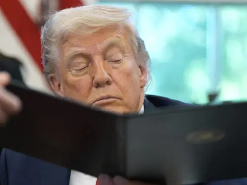 President Donald Trump is handed an executive order to sign by White House staff secretary Will Scharf in the Oval Office of the White House, Wednesday, April 23, 2025, in Washington.