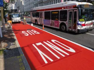 Workers paint on the bus only lane as a SEPTA bus passes in Center City, Philadelphia, Monday, Aug. 4, 2025.