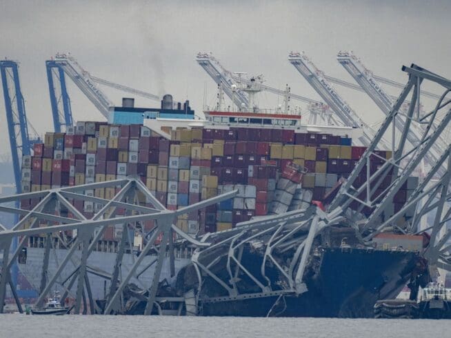 The container ship Dali, owned by Grace Ocean PTE, rests against wreckage of the Francis Scott Key Bridge in the Patapsco River on Wednesday, March 27, 2024, as seen from Pasadena, Md. Investigators began collecting evidence Wednesday from the cargo ship that plowed into Baltimore’s Francis Scott Key Bridge and caused its collapse, while in the waters below divers searched through twisted metal for several construction workers who plunged into the harbor and were feared dead. (AP Photo/Alex Brandon)