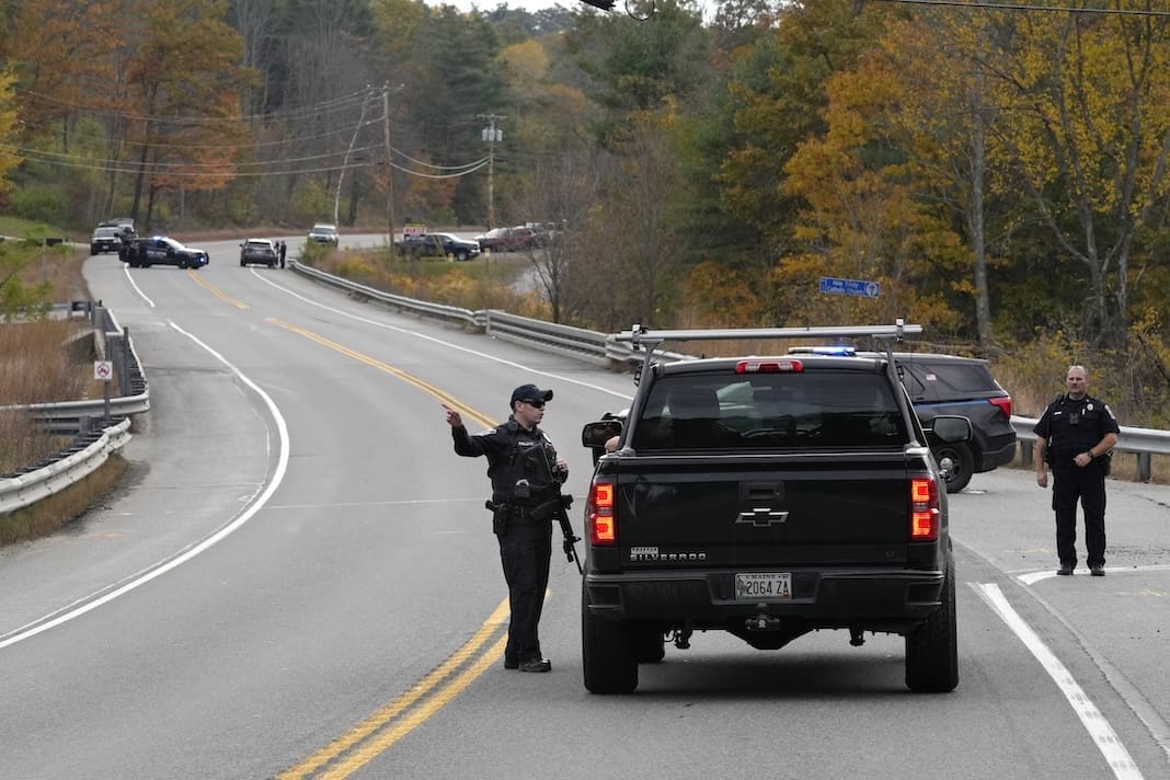 Police officers speak with a motorist at a roadblock, Thursday, Oct. 26, 2023, in Lisbon, Maine, during a manhunt for the suspect of Wednesday's mass shootings. The shootings took place at a restaurant and bowling alley in nearby Lewiston, Maine. (AP Photo/Robert F. Bukaty)