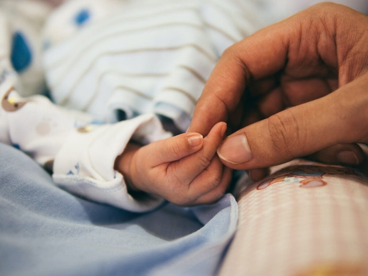 Person holding a newborn's hand.