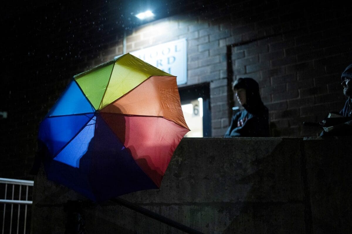 Central Bucks School District high school student Leo Burchell waits for a school board meeting to start, opening his rainbow colored umbrella as it begins to rain in Doylestown, Pa., on Tuesday, Nov. 15, 2022.