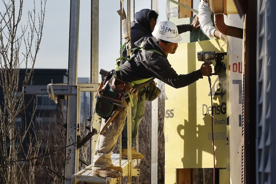 Workers apply sheathing to the exterior of a new multifamily residential building, Friday, Nov. 3, 2023, in the East Boston neighborhood of Boston. (AP Photo/Michael Dwyer)